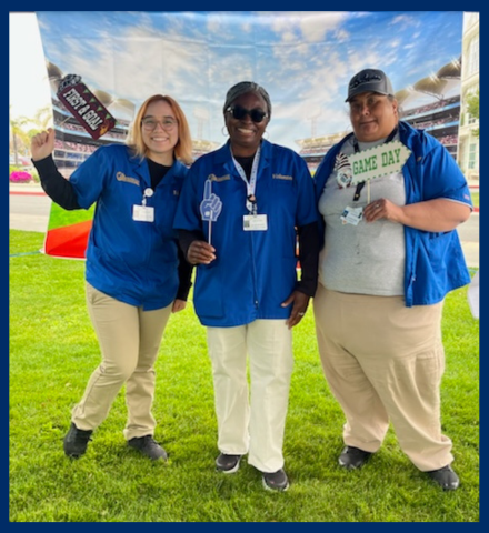 Three volunteers smile outside for a picture.